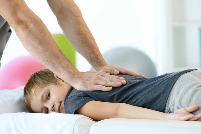A physical therapist guides a patient through a gentle stretching exercise on a treatment table.