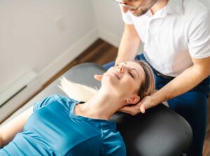 Person seated safely while a clinician assesses neck movement and balance during a vertigo evaluation.