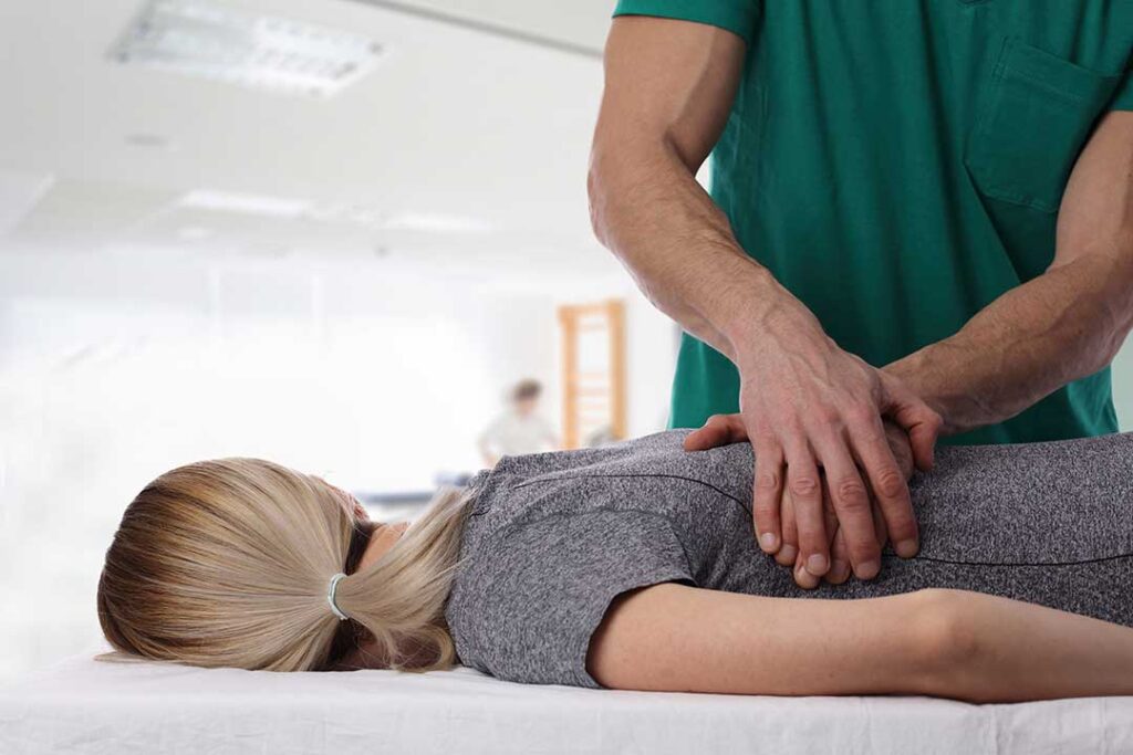Person doing gentle stretching beside a chair with a heat pack and symptom journal nearby.