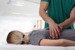 Person doing gentle stretching beside a chair with a heat pack and symptom journal nearby.