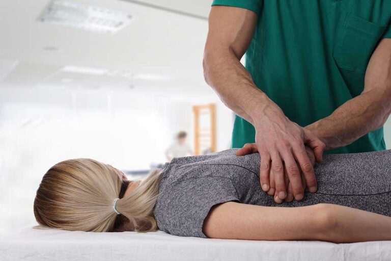 Person doing gentle stretching beside a chair with a heat pack and symptom journal nearby.