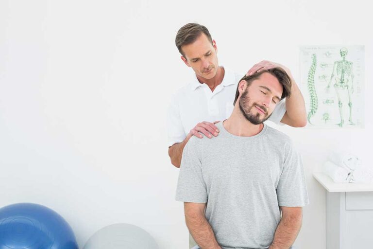 Person applying a wrapped cold pack to the lower back while seated at home.
