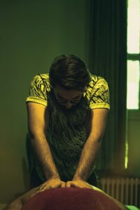 A clinician evaluates a seated adult’s neck and upper back movement in a bright examination room.