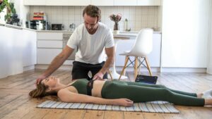 Person receiving a careful spine movement assessment while seated in a bright clinical room.